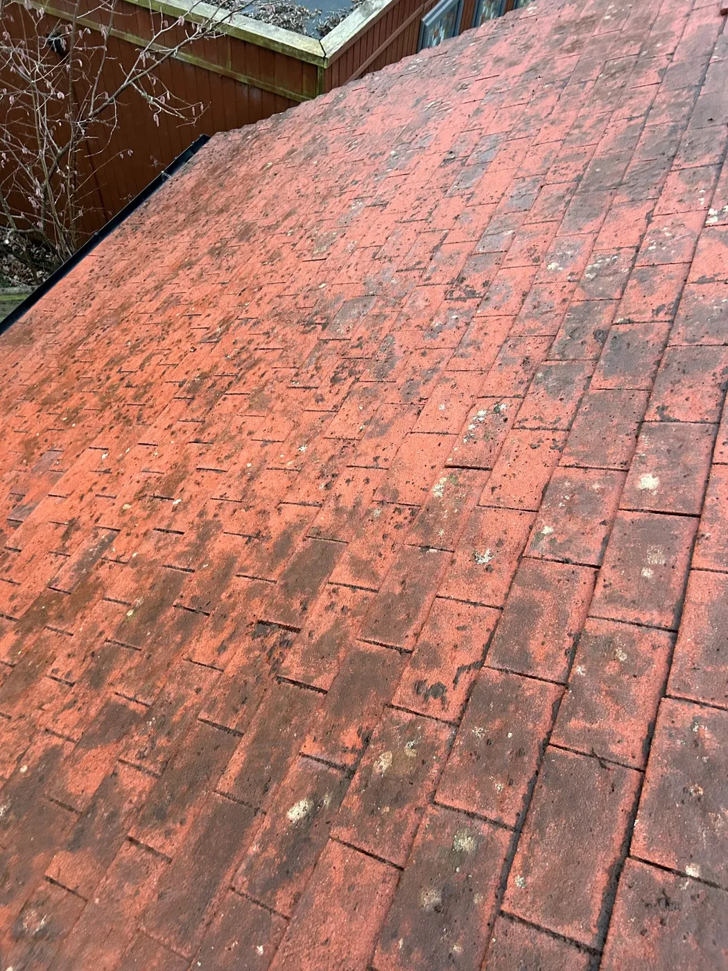 Red concrete roof tiles soiled with moss and lichen